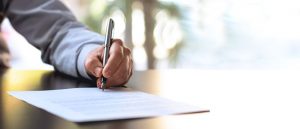 Man holding pen and signing the document